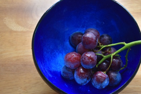 Love Coco coconut bowl with shiny blue interior, containing a bunch of red grapes